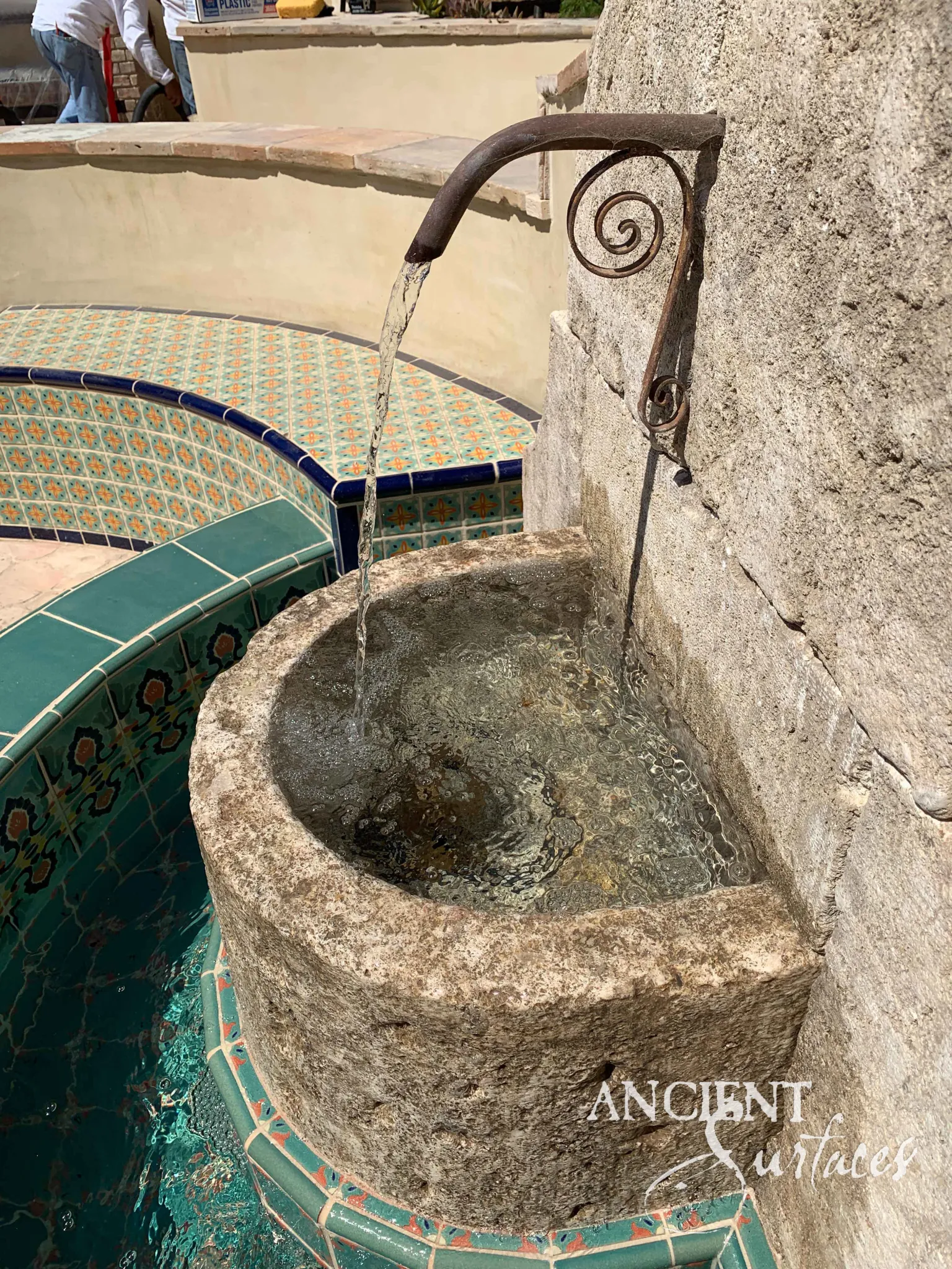 Rustic reclaimed limestone wall fountain with a carved foliate crest and curved stone basin